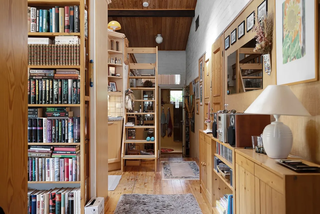 Étagère en bois remplie de romans et beaux livres, avec espace libre mesuré entre deux tablettes